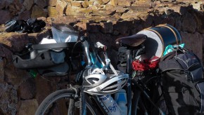 a bicycle loaded with gear leans against a rock wall