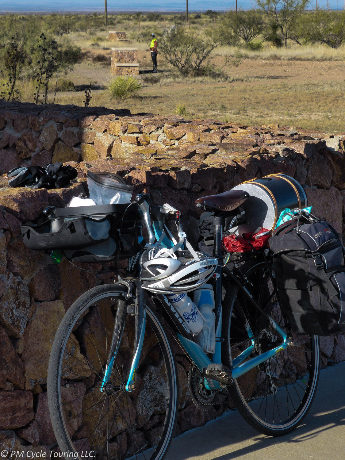 a bicycle loaded with gear leans against a rock wall