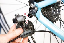 Hand holding rear derailleur near bicycle frame before attaching it.