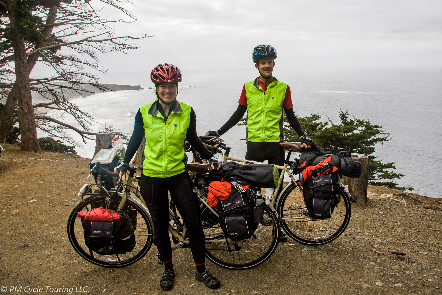 Two bicyclists and their bicycles and gear overlooking the ocean