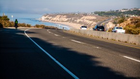 A bicycle rider climbing a hill near the ocean in La Jolla, California