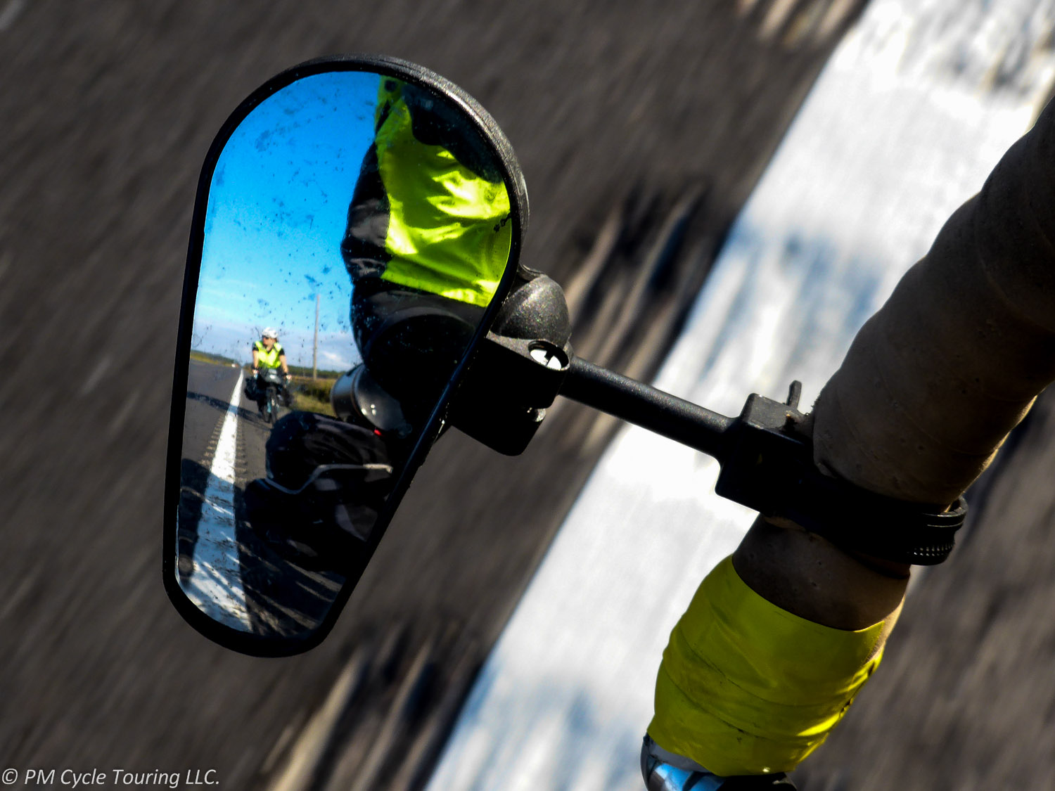 A clamp on bicycle mirror shows a cyclist behind.