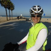 A cyclist faces the camera and smiles with a bike path in the background.