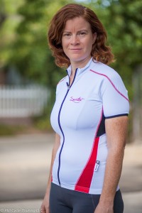 A woman wearing a short sleeve, white, full zippered cycling jersey