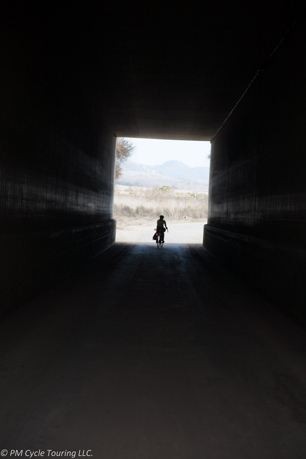 A bicycle tourist rides through a tunnel