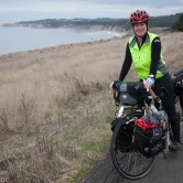 A woman on a touring bicycle stopped near the Pacific Ocean