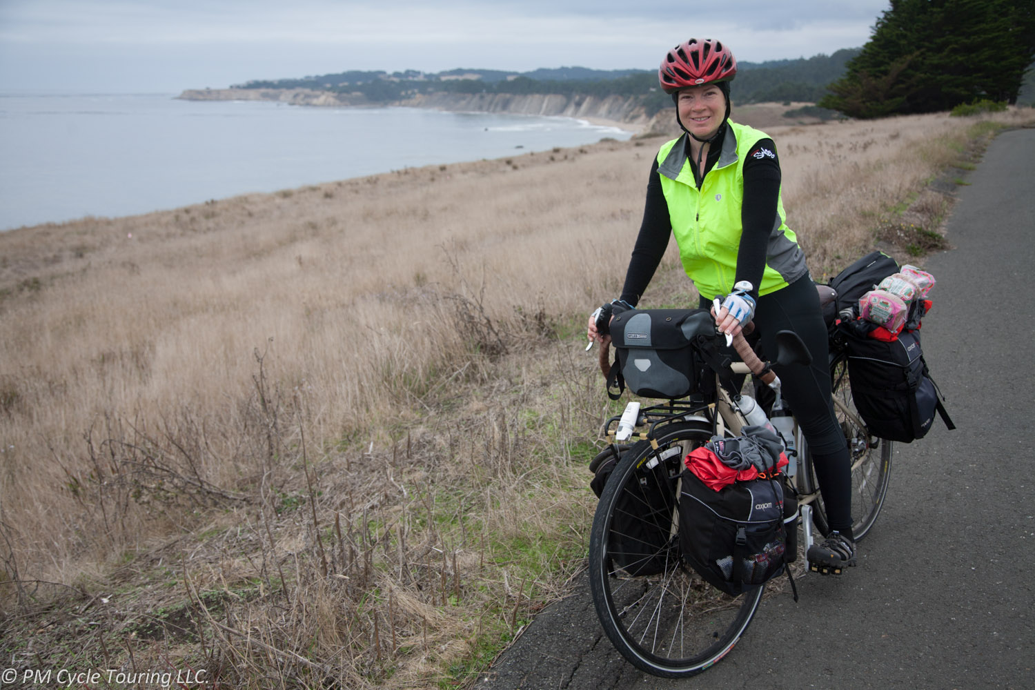 A woman on a touring bicycle stopped near the Pacific Ocean