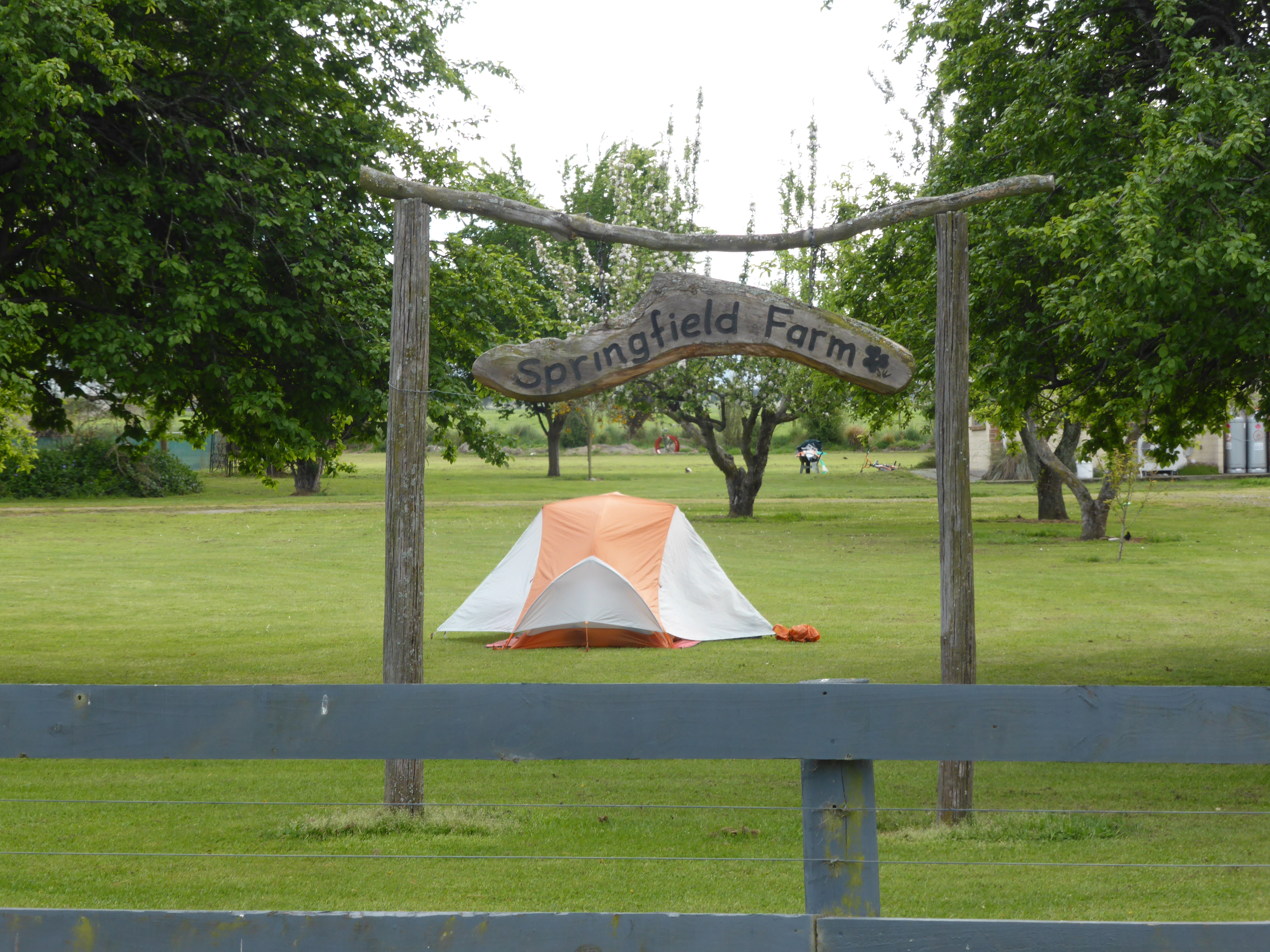 a tent set up in a field, framed by a farm sign